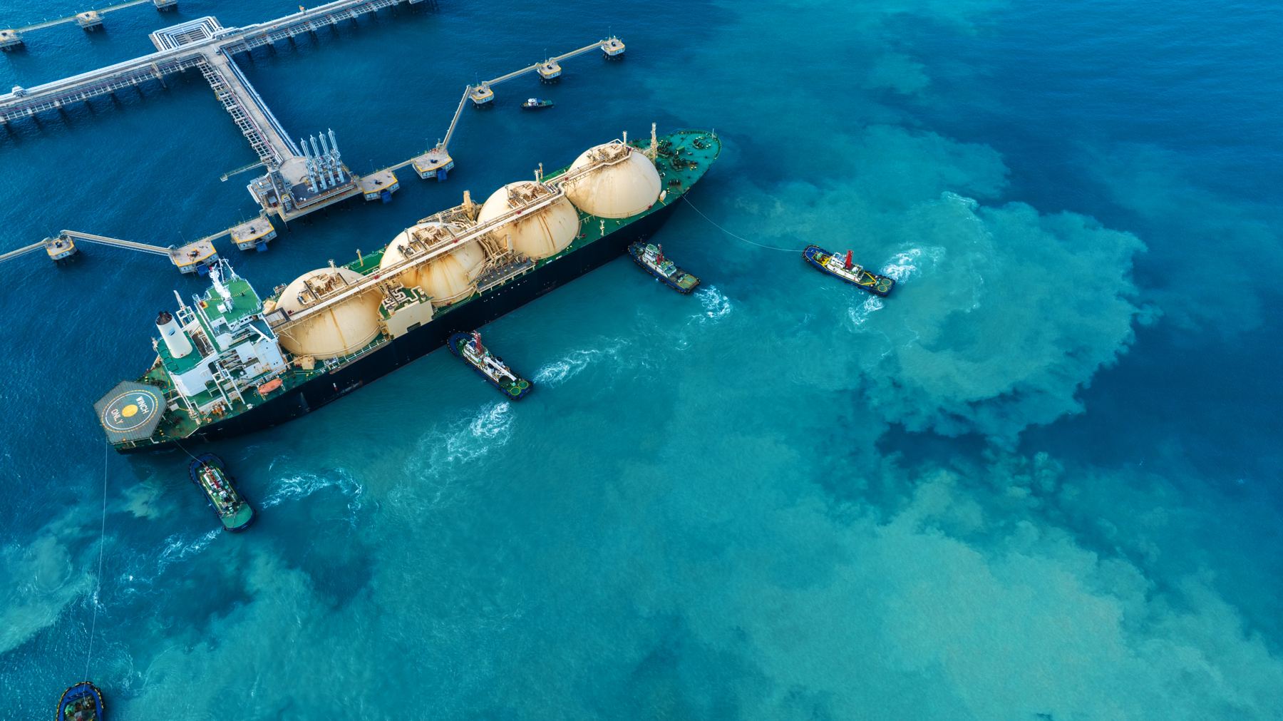 Aerial view of an LNG carrier moored at a jetty in turquoise water
